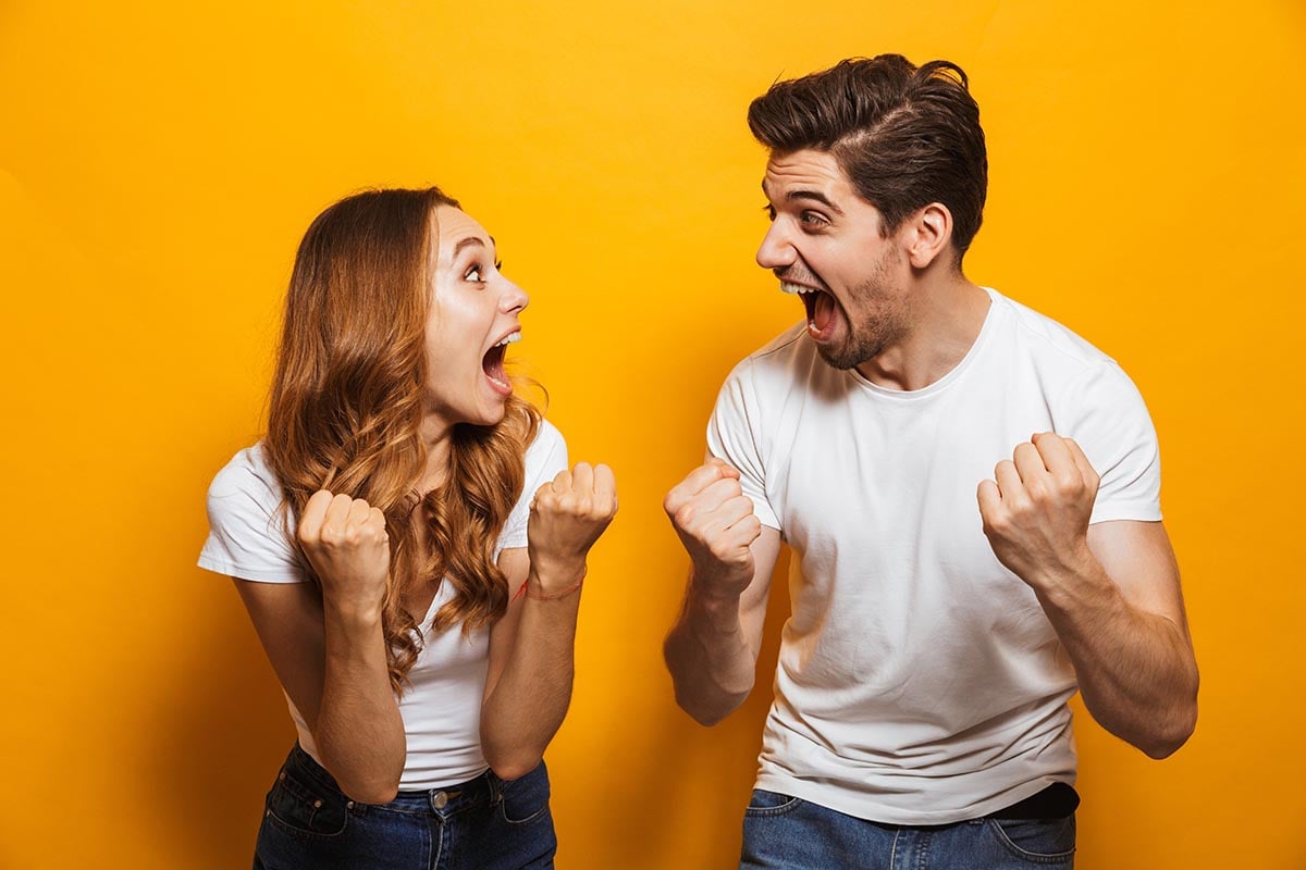 Ein Mann und eine Frau vor einem orangefarbigen Hintergrund, die sich freuen