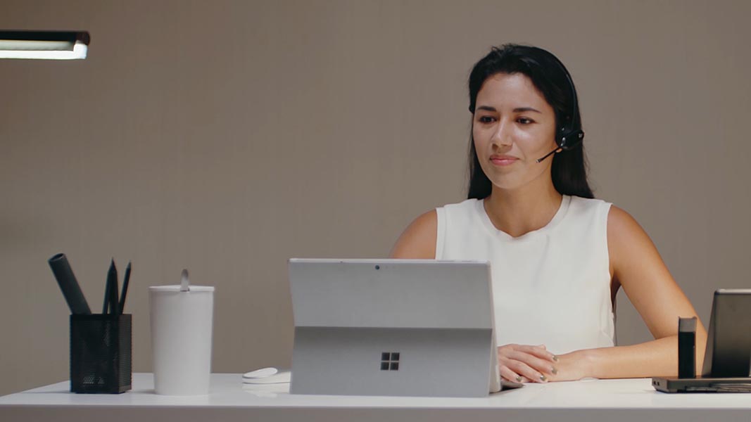 Eine Frau mit einem Headset sitzt am Computer - Symbolfoto für den Kundenservice Eine Frau mit einem Headset sitzt am Computer - Symbolfoto für den Kundenservice